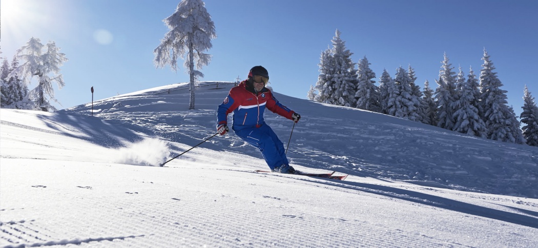 Skilehrer auf der präparierten Piste / im Hintergrund strahlender Sonnenschein